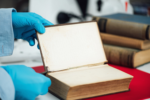 Book restoration process. Hands of a book conservation expert, repairing an antique book