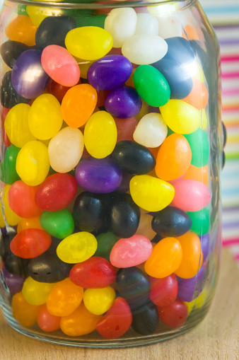 An assortment of jelly beans in a glass jar with clasp lid.  Isolated on white background.  Copy space on right side.