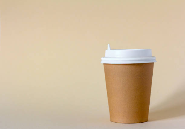 A paper cup for takeaway coffee on a light beige background.