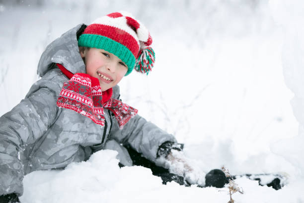 istock A little boy in a red knitted hat plays in the snow. 1409719261