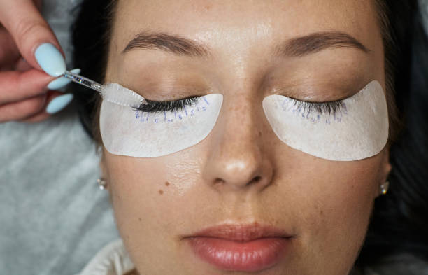 istock closed eyes with extended eyelashes and adhesive patches under them. eyelashes are extended on one eye and the brush combs them 1409719764
