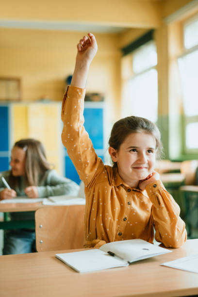 istock smiling school Girl raising hands during lecture in classroom 1409720980