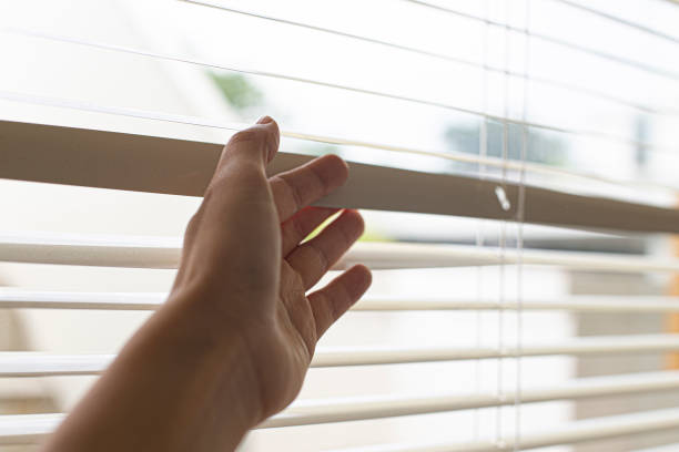 istock Woman's hand taking a peak through the window blinds. 1409720996