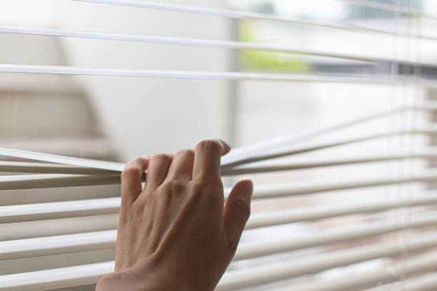 istock Woman's hand taking a peak through the window blinds. 1409721023