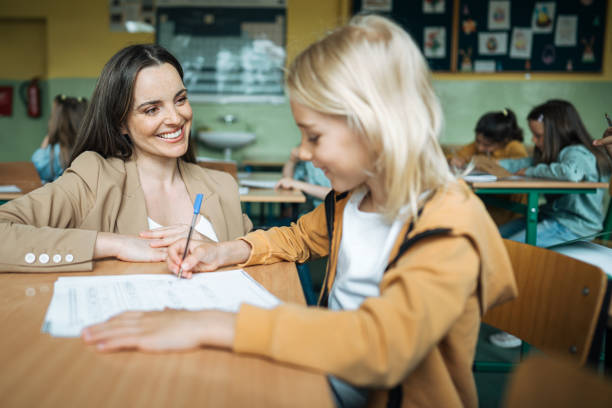 istock Smiling teacher listening to student's doubts while teaching him in classroom 1409722289