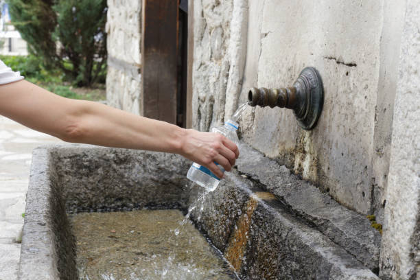 istock Woman`s hand holding plastic water bottle and refill with fresh spring water 1409722586