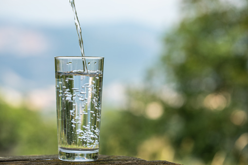 A glass of water a background of mountains, closeup, copy space, blurred background