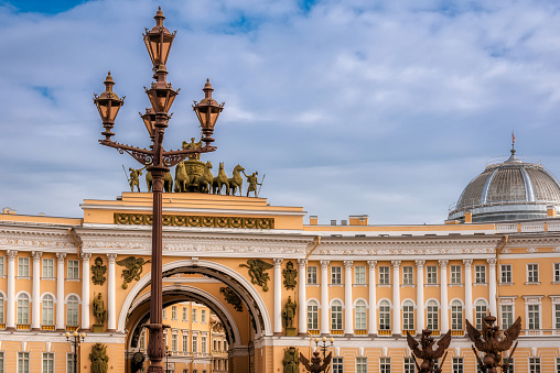 An ornate wrought iron street lantern with the General Staff Building in the background in the Palace Square of Saint Petersburg, Russia