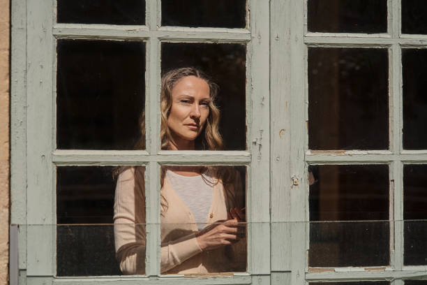 istock Melancholic woman looking at the window with sad face while thinking about her problems 1409725606