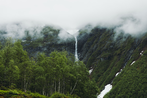 Scenic view of the hige waterfall and the green cliffs with Jostedal glacier above in Vestland County, Norway