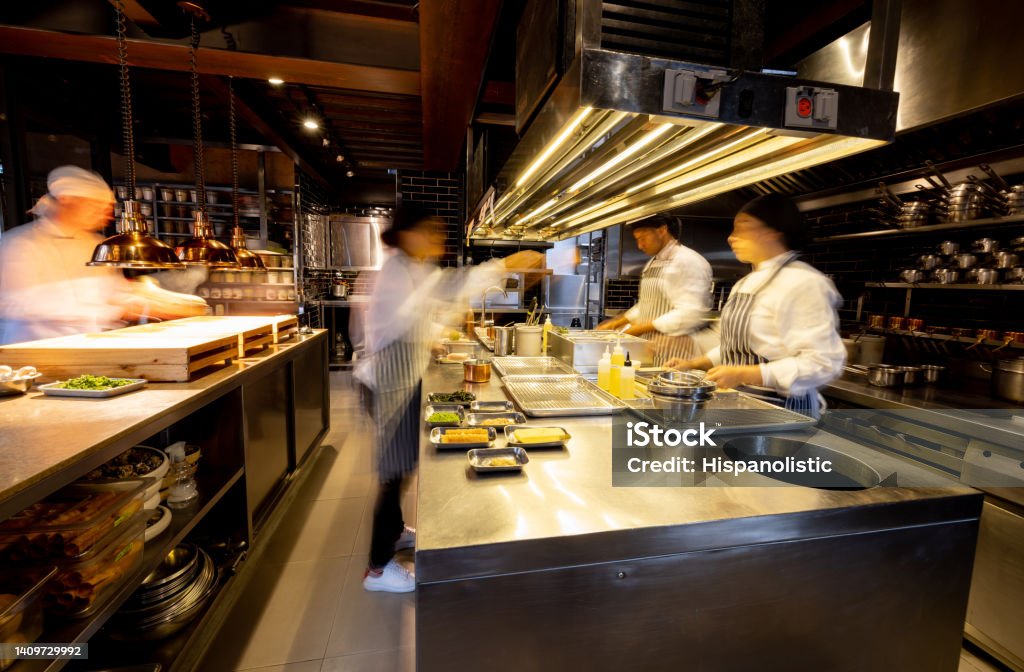 Hectic cooks working in a busy commercial kitchen at a restaurant Hectic cooks working in a busy commercial kitchen at a restaurant - food and drink establishment concepts Restaurant Stock Photo