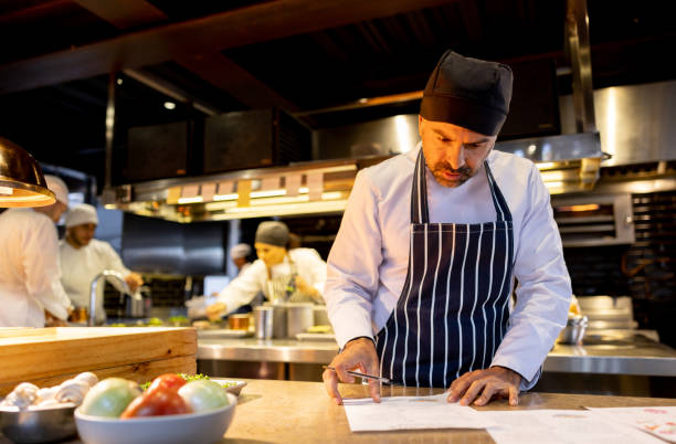 istock Chef working at a restaurant and looking at the recipes for the menu 1409729997