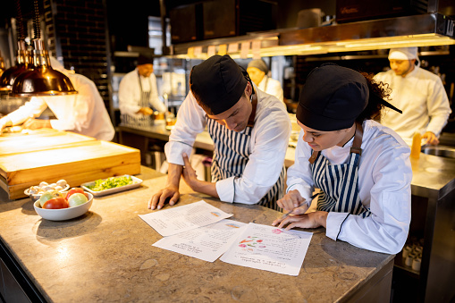 Team of cooks working at a restaurant and looking at a recipe