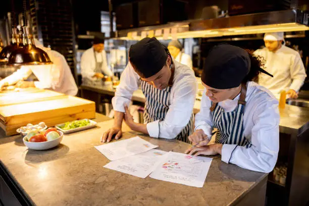 Photo of Team of cooks working at a restaurant and looking at a recipe