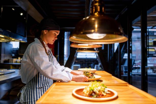 istock Cook working at a restaurant and placing a plate under a hot lamp to be served 1409730041