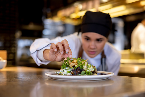 Latin American chef decorating a plate while working at a commercial kitchen
