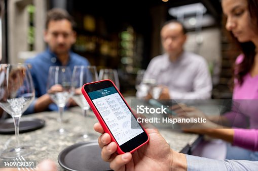istock Close-up on a man at a restaurant looking at the menu on his cell phone 1409730391