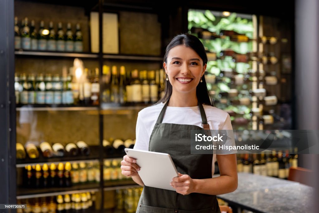 Happy waitress working at a restaurant Portrait of a happy Latin American waitress working at a restaurant and looking at the camera smiling Entrepreneur Stock Photo