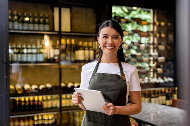 Happy waitress working at a restaurant Portrait of a happy Latin American waitress working at a restaurant and looking at the camera smiling cafe tablet stock pictures, royalty-free photos & images