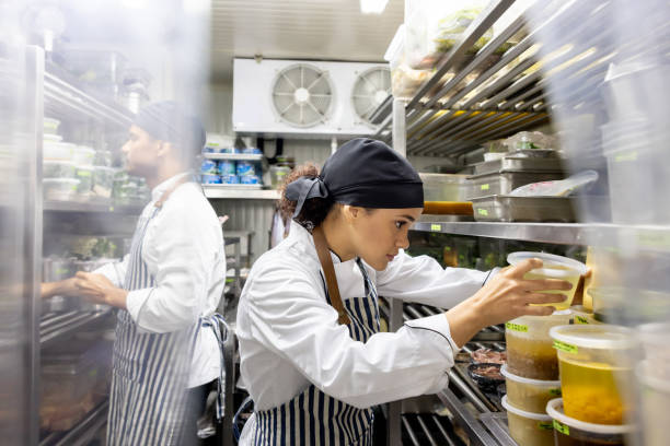 cooks working at a restaurant and looking for ingredients in the pantry - commercial kitchen restaurant chef food service occupation imagens e fotografias de stock