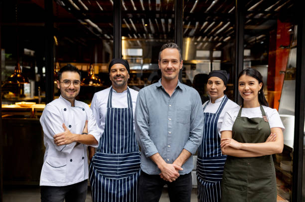 propriétaire de l’entreprise avec son personnel dans un restaurant - tenue de chef cuisinier photos et images de collection