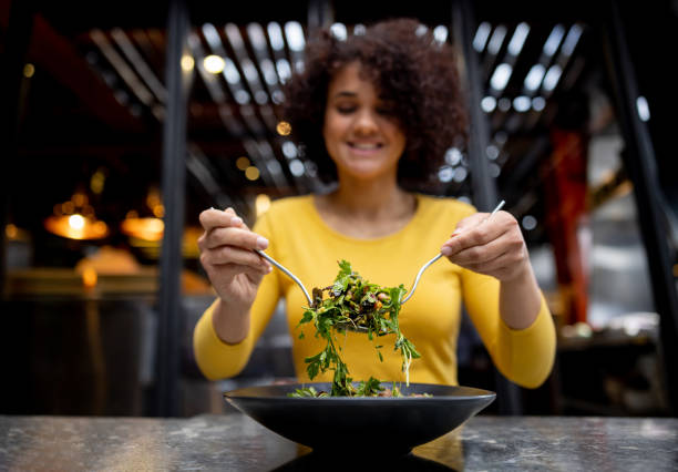 femme en bonne santé mangeant une salade dans un restaurant - vegetarians photos et images de collection