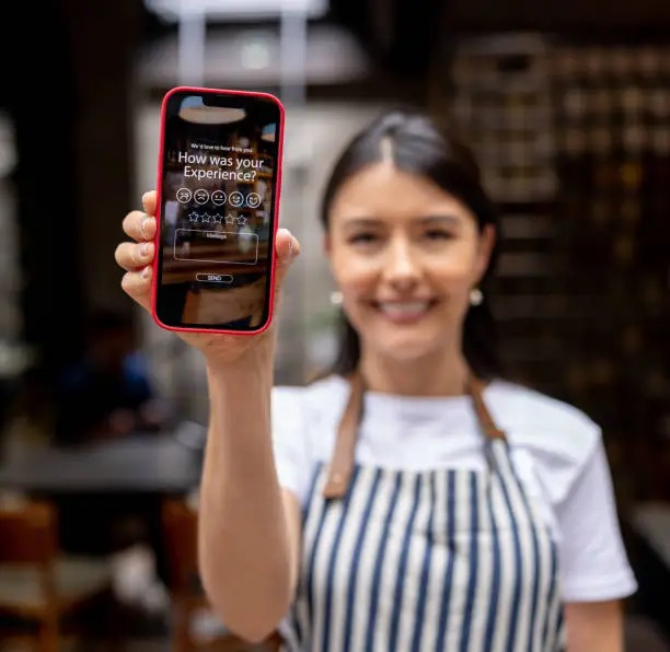 Photo of Waitress at a restaurant displaying an app to rate your experience