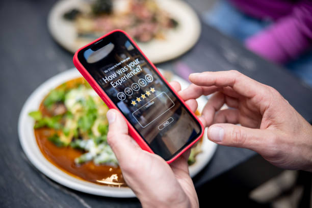 hombre calificando su experiencia en un restaurante usando una aplicación en un teléfono celular - restaurant review fotografías e imágenes de stock