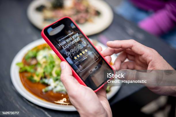 Man Rating His Experience At A Restaurant Using An App On A Cell Phone Stock Photo - Download Image Now