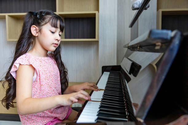 귀여운 아시아 소녀는 노래 작곡과 음악 교육 개념을 위해 집에서 클래식 피아노 레슨을 연습하고 있습니다. - music learning child pianist 뉴스 사진 이미지