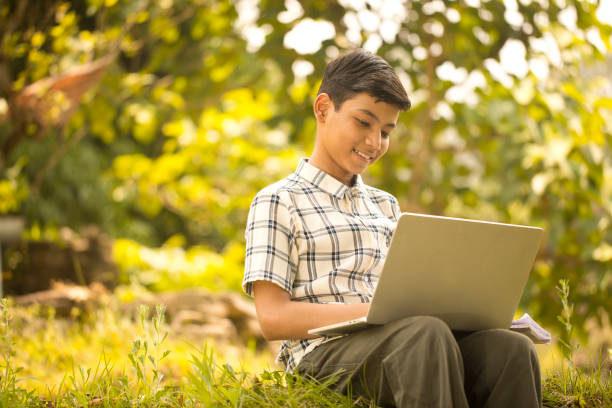 istock Teenage boy using laptop while sitting outdoors on rural ground 1409735711