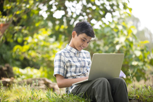 istock Teenage boy using laptop while sitting outdoors on rural ground 1409735733