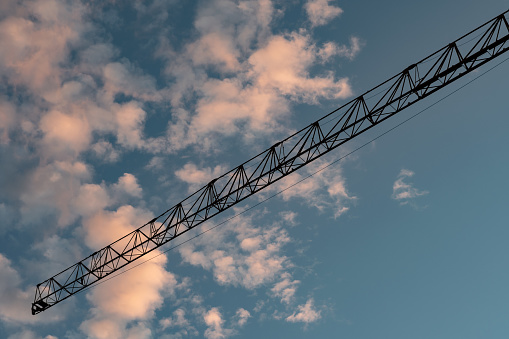 Crane construction tower on the cloudy bright blue sky background