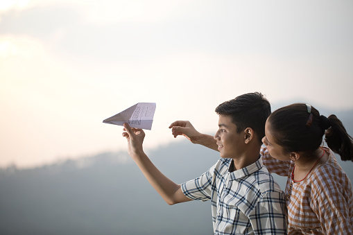 Teenage brother and sister having fun flying paper airplane