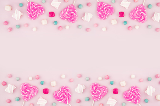 Pink lollipops, candy, caramel and marshmallows. Bright sweets and Valentine's Day. Top view flat surface with space to copy