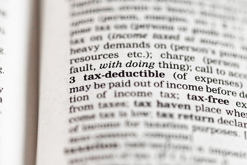 Macro image of a dictionary definition of the phrase 'tax-deductible'.