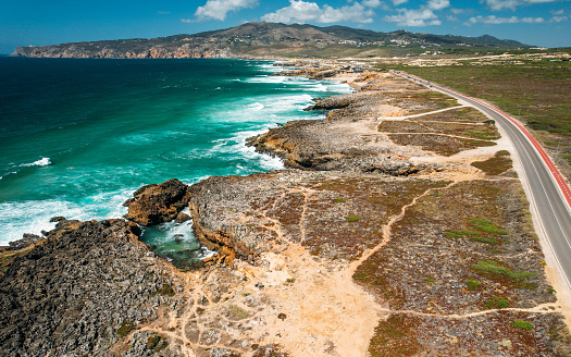 Aerial view view of of a N247 street with rugged coastline at Guincho beach, Cascais, Portugal. Cabo da Roca continental Europe's westernmost point is visible on far left