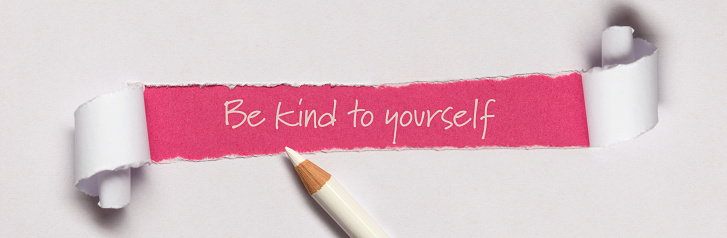 Be kind to yourself written under torn paper.