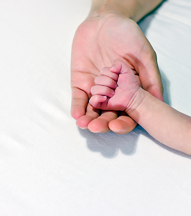 hands of a newborn baby with the nails, holding his mothers hand