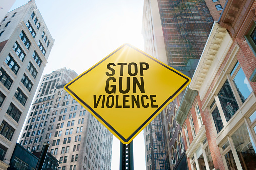 Road sign quoting “Stop gun violence” in an urban background