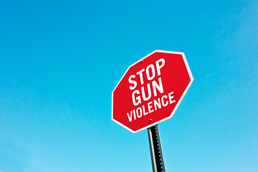 Stop gun violence sign pin front of a blue sky