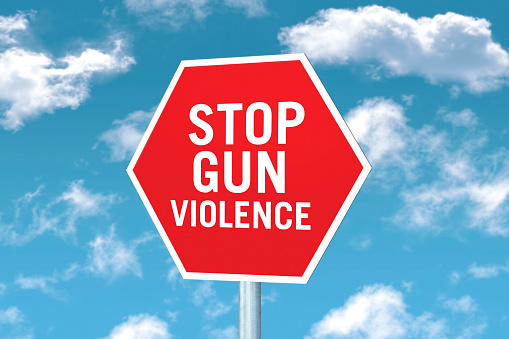 Stop gun violence sign pin front of a blue sky