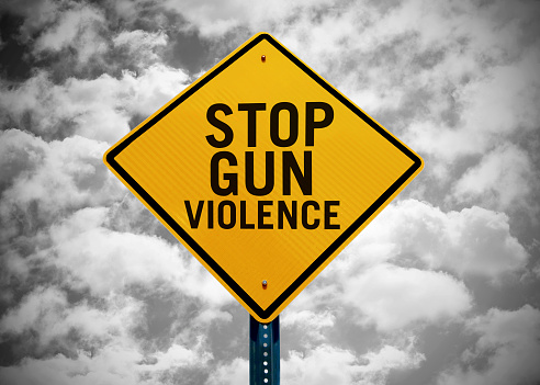 Stop gun violence sign pin front of a cloudy sky