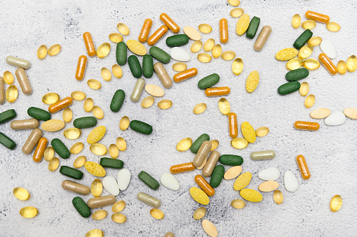 Various medicine pills scattered all over a rustic table. Many different colors, shapes and sizes. Perfect for both topics of abuse and of health