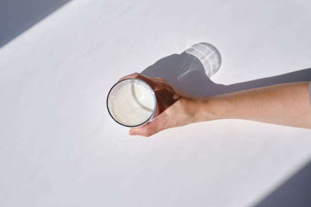 A glass of milk drink or yogurt in the hands of a girl. The concept of lactose intolerance. Transparent glass with tasty milk stock photo