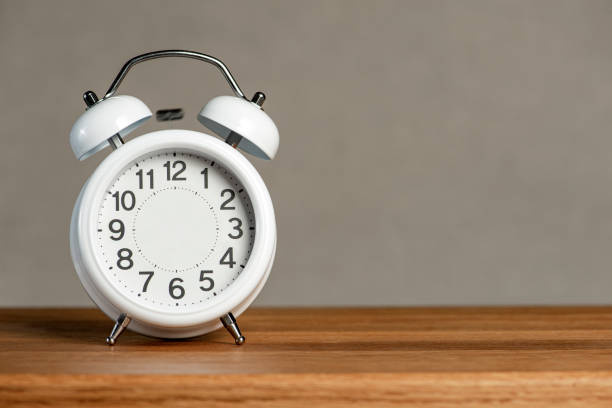 istock Alarm clock without arrows. White classic alarm clock on a wooden background without hands, space to insert text or copy. The concept of endless time, wasted time. 1409751167