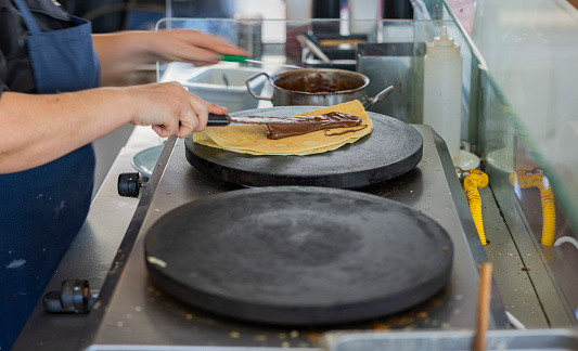 Close up view of woman baking crepes,  thin type of pancakes. Greece.