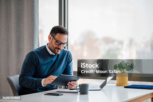 istock Young businessman using digital tablet while working in business office. 1409751960