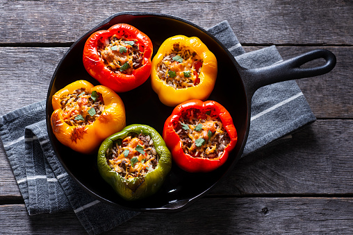 Raw quinoa stuffed sweet peppers in a cast iron skillet. Top view. Healthy, vegetarian food concept