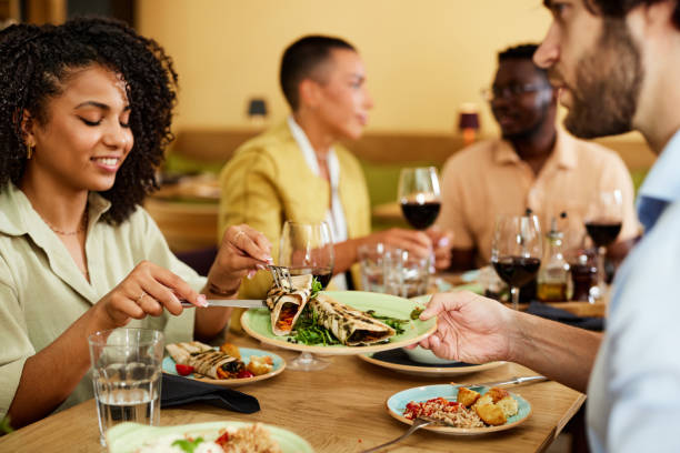 istock A happy multicultural couple sits in a restaurant with their friends and eats dinner. 1409753022